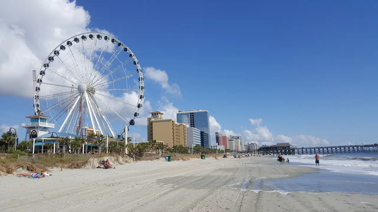 The SkyWheel Ferris wheel on the beach at Myrtle Beach, South Carolina, with oceanfront hotels and a fishing pier in the distance