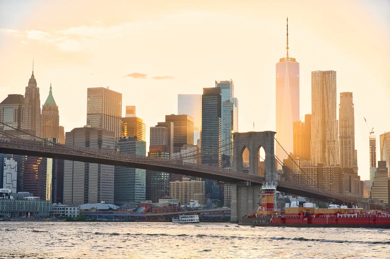 The Brooklyn Bridge and the Lower Manhattan skyline with One World Trade Center at golden hour, seen from the East River