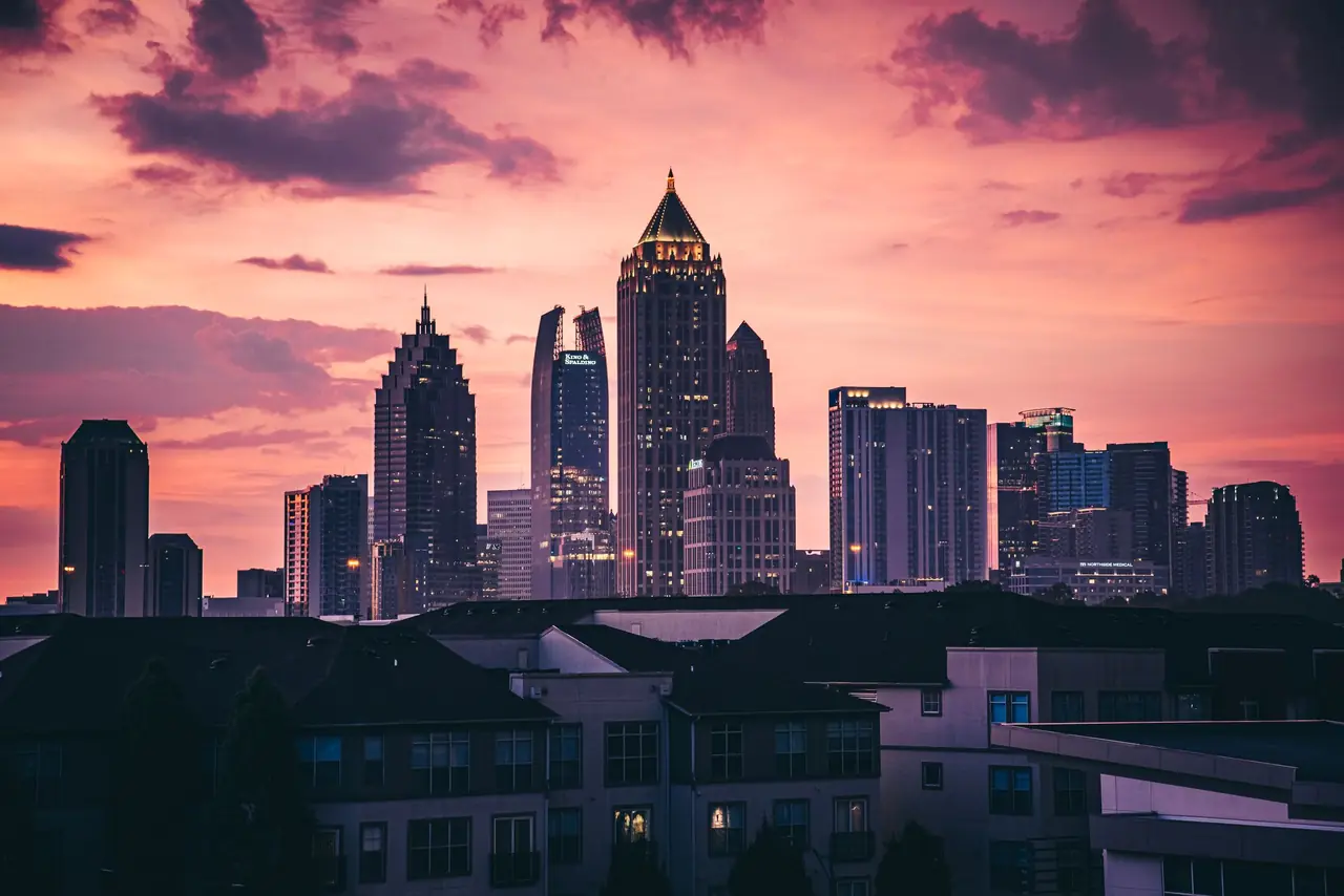 Midtown Atlanta's skyline silhouetted against a pink and violet sunset