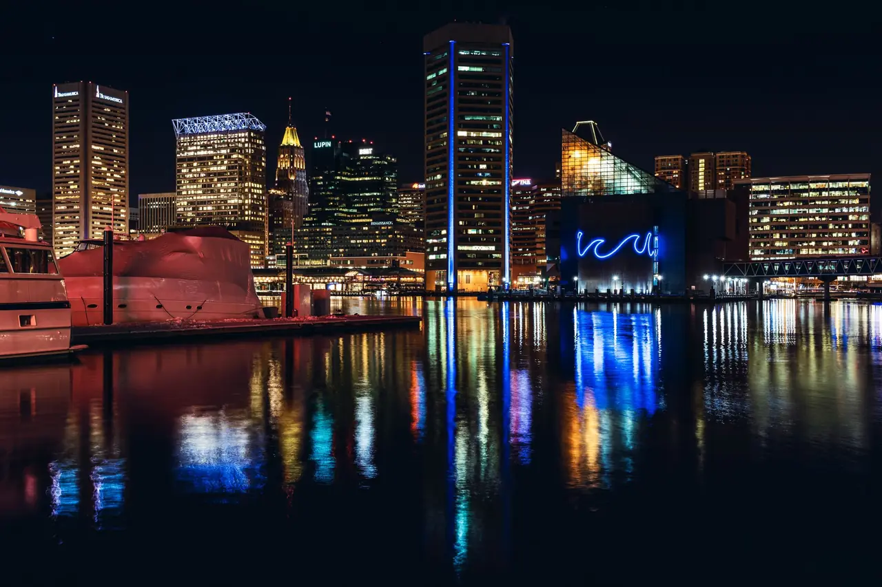 Baltimore's Inner Harbor at night, with the National Aquarium and downtown towers reflected in the water
