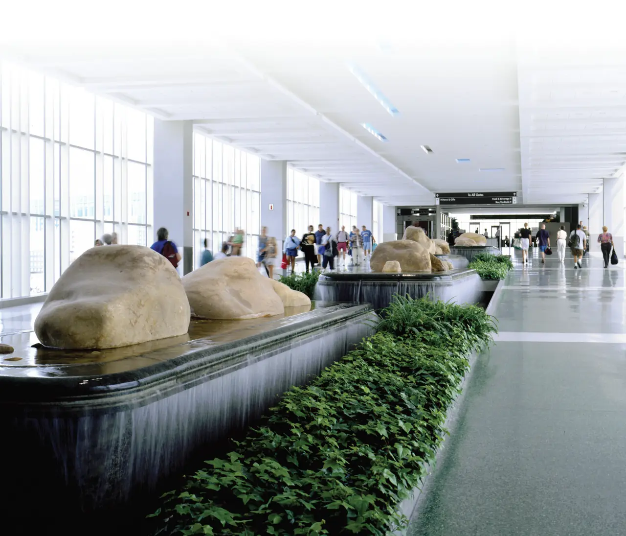 The bright main concourse at McGhee Tyson Airport (TYS), with river-rock water features and plantings along the walkway