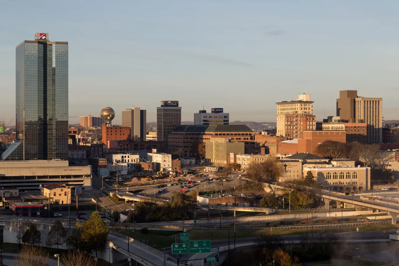 Downtown Knoxville in warm late-day light, with the glass First Horizon Plaza tower at left and the Sunsphere in the distance